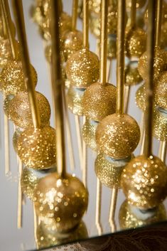 gold glitter cake pops are lined up on a table