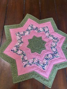 a pink and green quilted star on a wooden floor