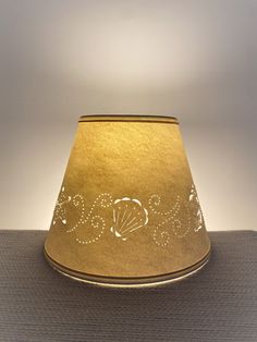 a gold lamp shade with the word seas written in cursive writing on it