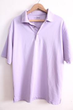 "Pastel lilac colored polo shirt with buttons at the top and loose fit. Ideal 90s basic in good condition. 'Grand Master Golf' brand 100% Polyester Size L Measures: 30\" length 23\" across chest 10\" sleeve 3.5\" tall collar B-3" Casual Purple Short Sleeve Polo Shirt, Purple Collared Cotton Top, Purple Cotton Collared Top, Casual Purple Cotton Polo Shirt, Classic Purple Short Sleeve Polo Shirt, Classic Purple Relaxed Fit Top, Purple Casual Polo Collar Shirt, Casual Purple Polo Collar Shirt, Casual Purple Polo Shirt