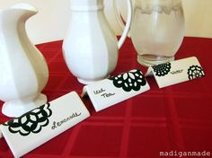 three white vases sitting next to each other on a red cloth covered tablecloth