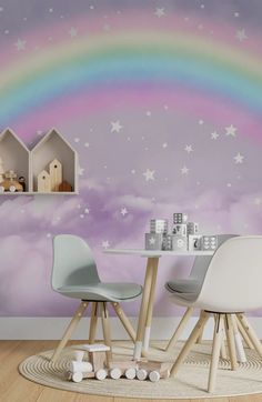 two chairs and a table in front of a wall with a rainbow painted on it