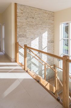 the sun shines through two windows in an empty room with stone wall and railing