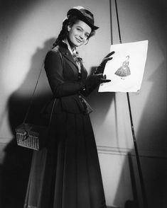 an old photo of a woman holding a piece of paper with a drawing on it