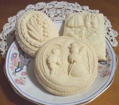 three cookies are sitting on a plate with lace doily around the edges and one cookie is decorated with an image of two children