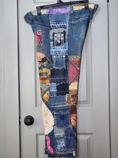 an old pair of jeans is hanging on the front door with some fabric and buttons attached to it