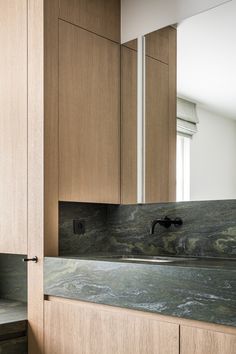 a bathroom sink sitting under a mirror next to wooden cabinets