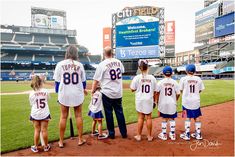 a group of people standing on top of a field wearing baseball uniforms and holding hands