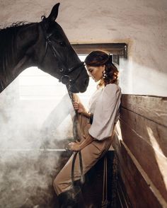 a woman standing next to a horse in a stable with steam coming out of it