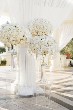 the flowers are in vases on the side of the wedding ceremony aisle, which is lined with white draping