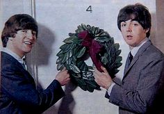 two men in suits holding a wreath over another man's head