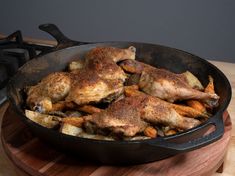 some chicken is cooking in a skillet on a wooden board next to a stove