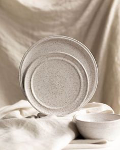 two white dishes sitting on top of a bed