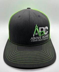 a black and green hat with the above board logo on it's side