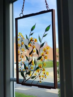 a window frame with yellow flowers hanging from it