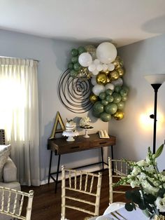 balloons are hanging on the wall above a table with chairs and a vase filled with flowers