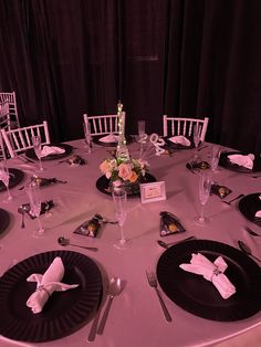 the table is set with black plates and silverware