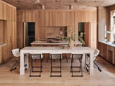 a kitchen with wooden walls and flooring next to a dining table surrounded by chairs