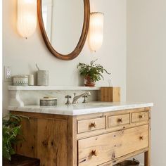 a bathroom with a sink, mirror and potted plant