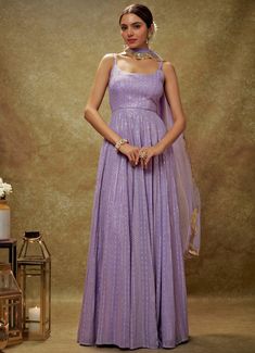 Embrace timeless elegance with the Lavender and Gold Sequin Embroidered Anarkali Gown, expertly crafted from luxurious viscose georgette. This lavender gown is adorned with intricate sequin and threadwork embroidery, bringing a touch of opulence to its design. The flattering strappy round neckline and chic back cutout at the waist introduce a modern flair to the traditional silhouette. Its flowy, floor-length design exudes regal charm, perfectly complemented by the matching net dupatta with delicately embroidered scallop lace. Ideal for Mehndi, Sangeet, or as wedding guest attire, this ensemble seamlessly blends classic allure with contemporary sophistication Composition : Anarkali - Viscose Georgette and Dupatta - Soft net Care: Dry Clean Only and Vacuum Storage This product can be custom Sequin Anarkali, Bridal Crop Top, Lavender Gown, Kurta Lehenga, Waistcoat Woman, Embroidered Anarkali, Indian Wedding Wear, Anarkali Gown, Guest Attire