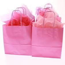 two pink shopping bags are sitting side by side on a white surface the bag is filled with tissue paper