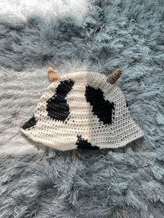 a crocheted cow hat laying on top of a blue fuzzy rug with horns