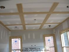 an empty room with three windows and some unfinished wood beams on the ceiling above them