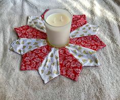 a candle sits on top of a red and white quilted star ornament