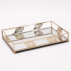 a mirrored tray with gold leaves on the front and bottom, sitting on a white surface