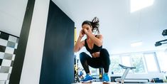 a woman in black top and leggings doing squat exercises on a white table