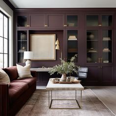 a living room filled with furniture and a large window covered in dark brown bookshelves