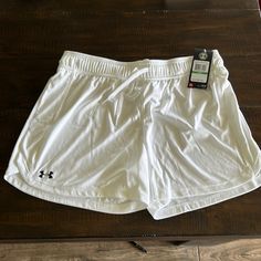 a pair of white shorts sitting on top of a wooden floor next to a cell phone