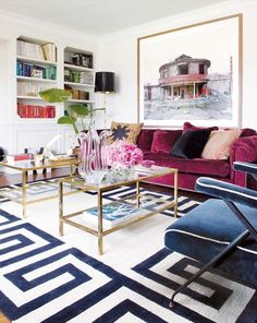 a living room filled with furniture and a painting on the wall above it's coffee table