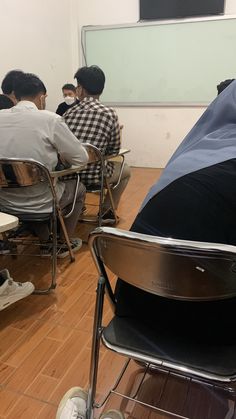 several people sitting at desks in front of a projector screen with one person on the floor