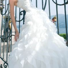 a woman in a wedding dress leaning against a gate