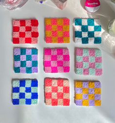 four squares made out of crochet sitting on top of a white table next to other items