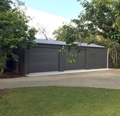 a garage with two doors on the side of it and trees in the back ground