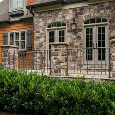 a stone house with two windows and a fenced in area next to the front door