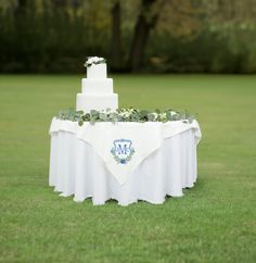 a wedding cake sitting on top of a table covered in white cloths and greenery