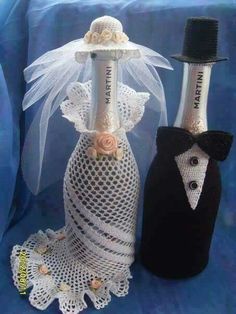 two wine bottles are decorated with lace and flowers, one has a bride's veil on it