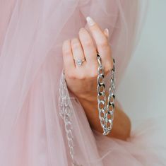 a woman wearing a pink dress and holding onto a chain with a ring on it