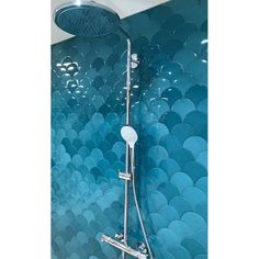 the shower head is attached to the wall with blue tiles on it and there are two faucets