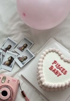 a birthday cake with pink frosting and pictures on it next to a camera, balloons, and other items