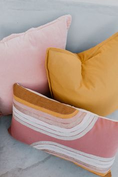 three different colored pillows sitting next to each other