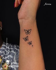 a woman's wrist tattoo with three butterflies on the left side of her arm