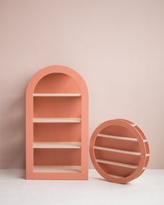 a pink book shelf next to a round shaped object on a white tablecloth covered floor