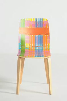 a colorful chair sitting on top of a white floor next to a wooden legrest