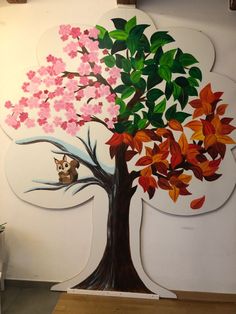 a tree painted on the side of a wall with leaves and flowers growing out of it