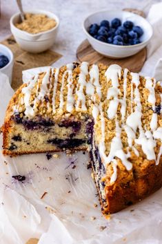 a blueberry cake is cut into slices and served with other desserts on the table