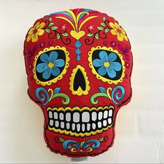 a red sugar skull pillow with blue flowers on it's side and eyes closed